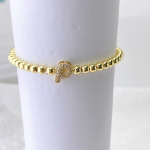Detalle de la pulsera de cuentas doradas con colgante de letra P y cristales brillantes