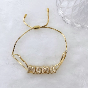 Macro detail of gold-plated MAMA bracelet with micro-pave cubic zirconia on plush background