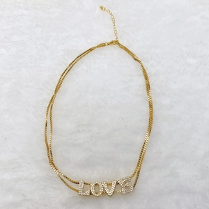 Macro detail of gold layered necklace with zircon LOVE pendant and lobster clasp
