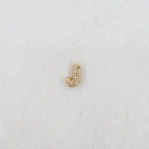 Macro detail of gold-plated J-shaped bubble charm with sparkling pavé cubic zirconia