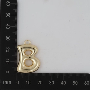 Détail montrant les dimensions du pendentif lettre B dorée 3D avec une règle de mesure