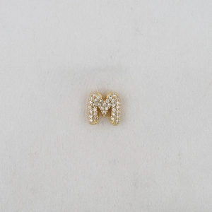 Macro detail of puffy bubble letter M pendant with sparkling pave zircon setting