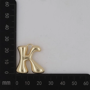 Vue détaillée du pendentif lettre K dorée avec règle de mesure montrant 30mm de haut