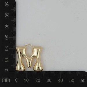 Vue macro d'un pendentif lettre M ballon doré brillant avec une finition métal liquide
