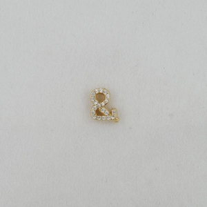Detailed close-up of a gold ampersand pendant with micro-pave cubic zirconia stones