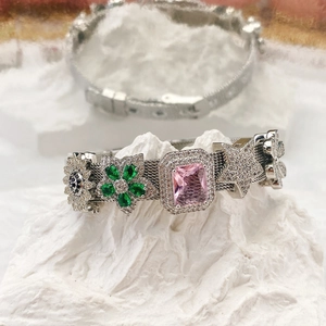 Silver mesh bracelet with colorful zircon charms on white textured stone base