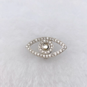 Macro shot of evil eye charm with sparkling white zircons on soft plush background