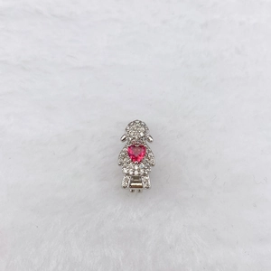 Macro shot of silver girl charm with sparkling pavé crystals and a red heart stone