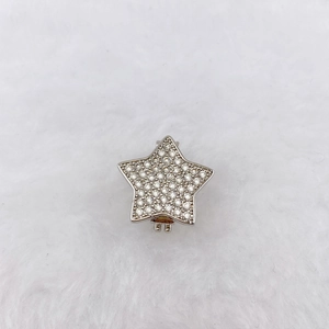 Detailed view of silver star charm with white cubic zirconia on soft white plush background