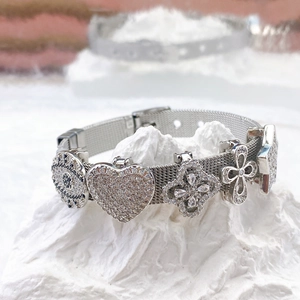 Silver stainless steel mesh bracelet with heart and crystal charms on a mineral stone