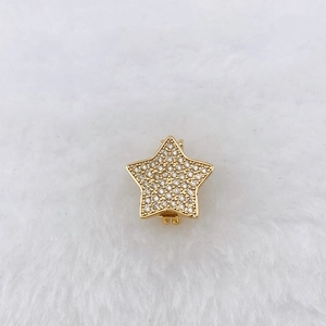 Detailed view of gold-plated star charm with cubic zirconia on white faux fur background
