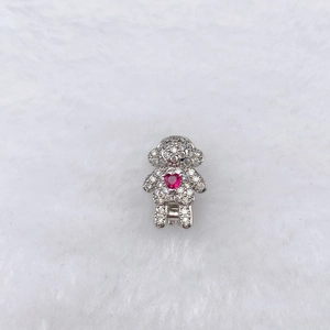 Macro shot of silver doll charm with pave white zircons and a red heart gemstone