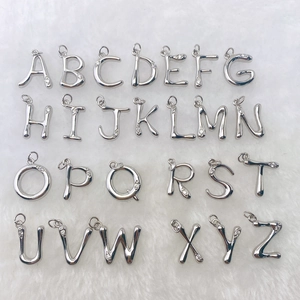 Silberne A-Z Buchstabenanhänger aus Messing mit Zirkonia auf weißem Fellhintergrund