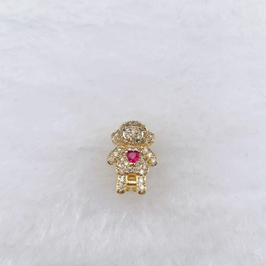 Macro view of golden bear charm with white zircon pavé and red heart stone detail