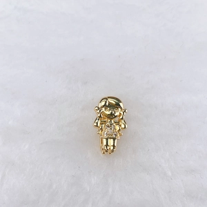 Close-up of golden girl charm with sparkling zircon crystals on soft white texture