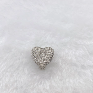 Macro view of heart-shaped silver charm with sparkling pavé zircons on white fur background