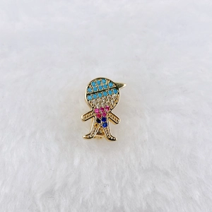 Detailed view of a golden boy pendant charm with blue and pink zircon stone inlays
