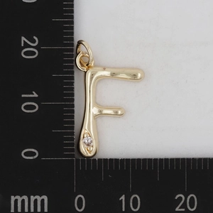 Makroansicht des goldenen Buchstaben-F-Anhängers mit Zirkonia auf Millimeterskala