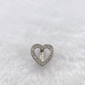 Macro detail of a silver heart charm with pavé crystals and a slider bar attachment