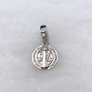 Détail macro d'un pendentif médaille de Saint-Benoît en argent avec gravure religieuse