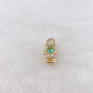 Macro detail of gold girl charm with green heart zircon and white pavé crystals