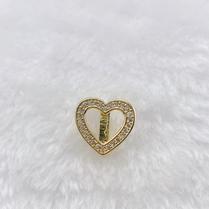 Close-up of golden hollow heart charm with paved zircon stones for mesh bracelet