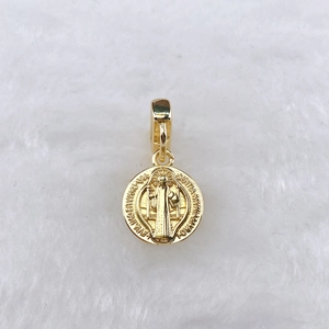 Gros plan détaillé d'un pendentif médaille Saint-Benoît doré avec relief sur fausse fourrure