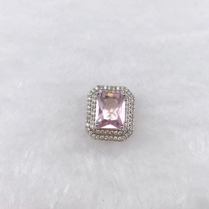 Macro shot of rectangular pink gemstone charm with double white zircon halo on silver setting