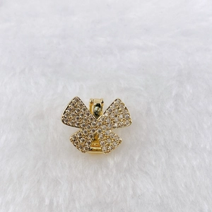 Detail of a gold butterfly charm with clear zircons on a white plush texture