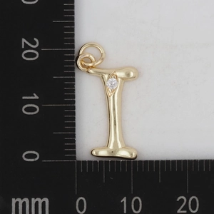 Makroaufnahme des Gold-Messing-Buchstaben-I-Anhängers mit Zirkonia auf einem mm-Lineal