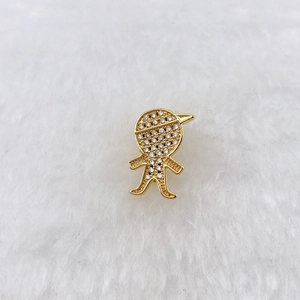 Macro detail of gold boy charm pendant with sparkling cubic zirconia on white fur background