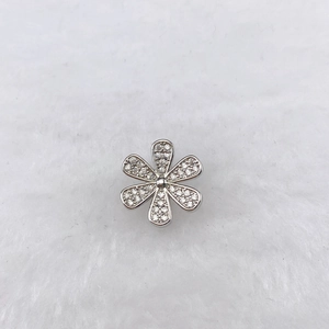 Macro shot of silver flower charm with zircon micro-pave on white plush background