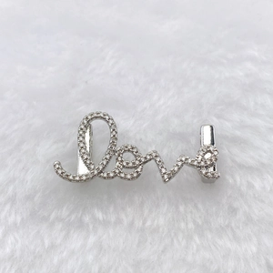 Macro shot of silver metal Love charm pendant with white cubic zirconia stones