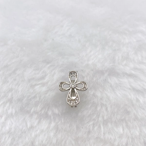 Detailed macro view of a silver cross charm featuring pavé-set clear cubic zirconia