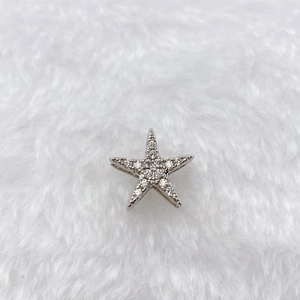 Detailed close-up of a silver star-shaped charm with cubic zirconia on white fur