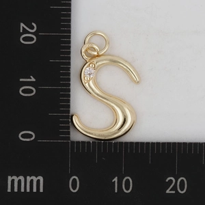 Makroansicht des goldenen Buchstaben-S-Anhängers mit Kristall auf einer Messskala