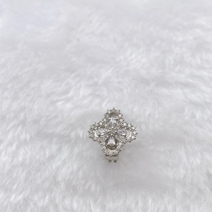 Macro shot of silver floral jewelry with clear zircons on white plush background