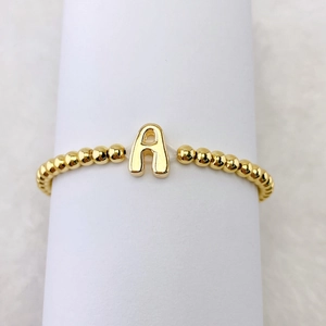 Detailansicht eines 18k vergoldeten Perlenarmbands mit Buchstabe A Anhänger auf Weiß