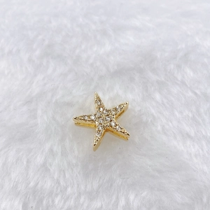 Macro shot of gold starfish pendant with white cubic zirconia on white fur background