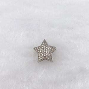 Macro detail of star-shaped charm with clear pave cubic zirconia and silver plating