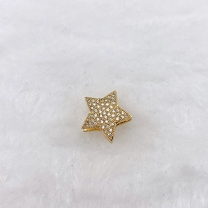 Macro shot of gold star-shaped charm with sparkling cubic zirconia on white fur backdrop