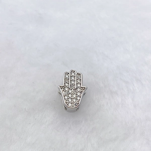 Vue macro d'un pendentif Main de Fatima en métal argenté avec des zircons étincelants