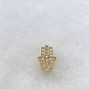 Macro d'une breloque Main de Fatima dorée sertie de zircons cubiques blancs scintillants
