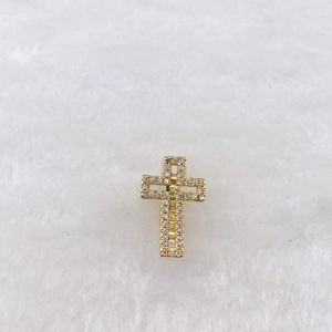 Detail of a golden cross pendant with micro-pave cubic zirconia on a soft white background