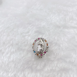 Detail of silver Virgin Mary oval charm with multi-colored crystals on white plush background