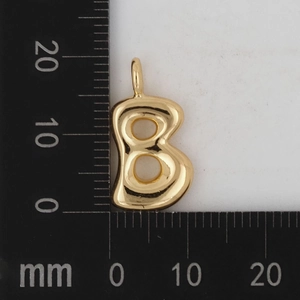 Detailaufnahme des 18K Goldbuchstaben B Anhängers auf einer Millimeterskala zur Größenmessung