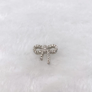 Detail shot of a silver bow charm with shimmering pavé cubic zirconia on plush white fur