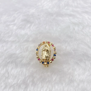 Detail of golden Virgin Mary pendant with colorful gemstones on white fur background