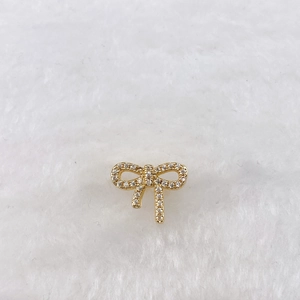 Detail of a gold plated bow charm accessory with pave set white cubic zirconia crystals