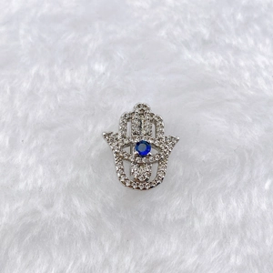 Macro detail of silver Hamsa Hand charm with pavé zircon and blue center stone inlay